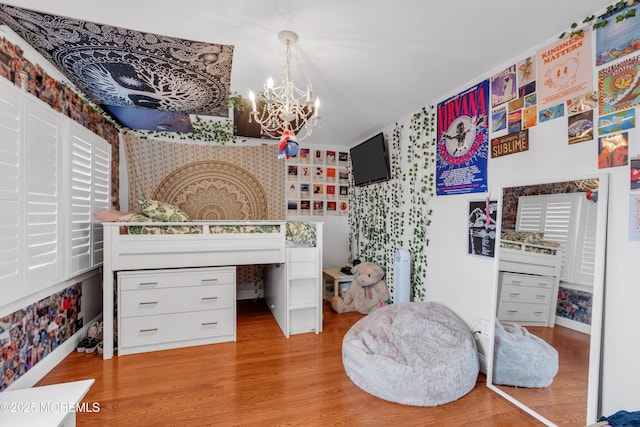 bedroom featuring wallpapered walls, light wood-type flooring, and a notable chandelier