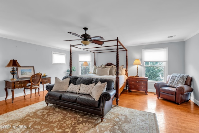 bedroom featuring baseboards, light wood finished floors, visible vents, and crown molding