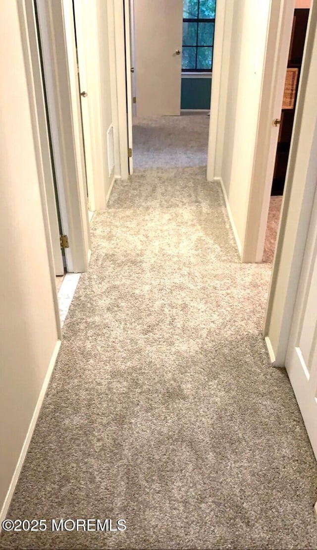 hallway with visible vents and light colored carpet