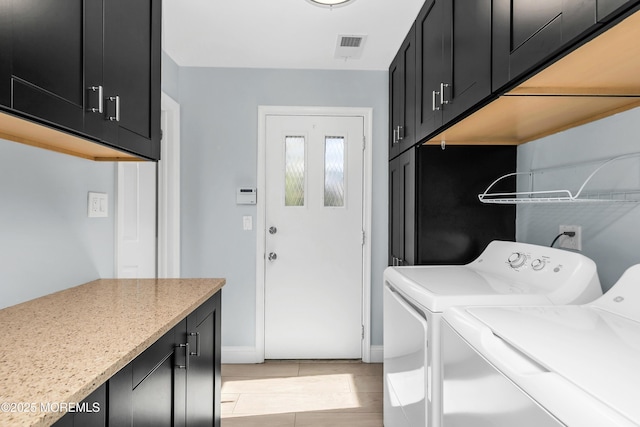 clothes washing area with cabinet space, visible vents, and washer and dryer