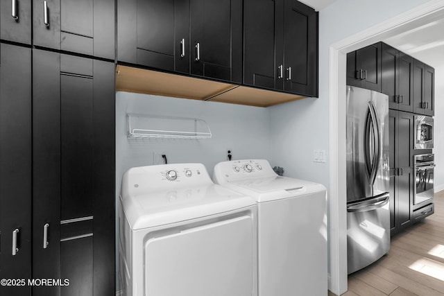 clothes washing area featuring light wood finished floors, independent washer and dryer, and cabinet space