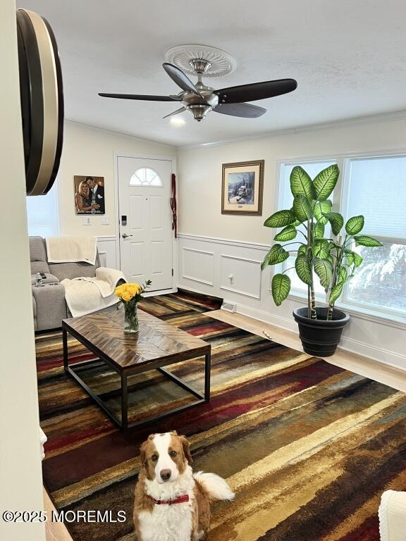 interior space with a wainscoted wall, ceiling fan, a decorative wall, and dark wood-style flooring