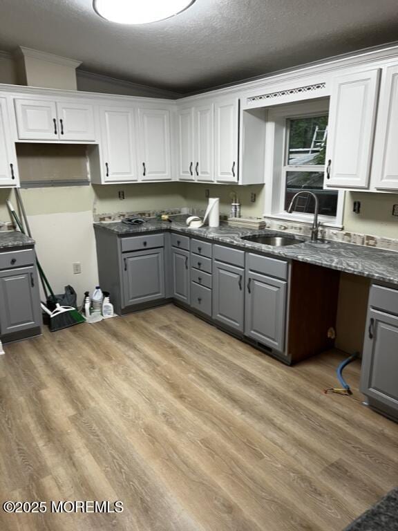 kitchen with dark countertops, white cabinetry, and a sink