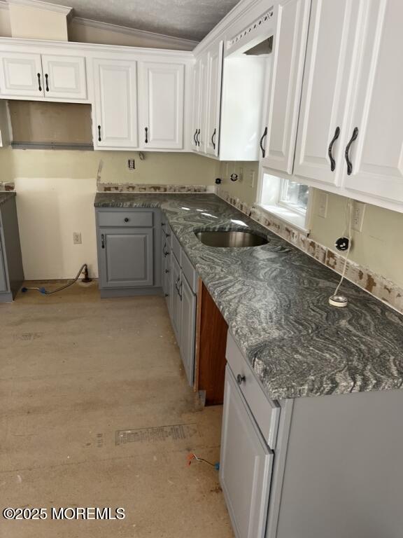 kitchen with ornamental molding, gray cabinets, white cabinets, and a sink