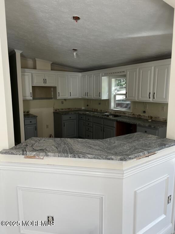 kitchen with a peninsula, a textured ceiling, and gray cabinetry