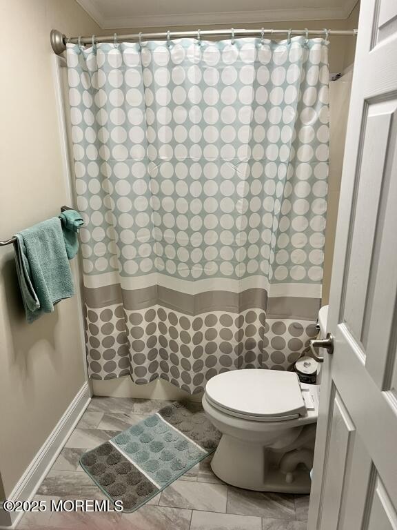 full bath featuring toilet, curtained shower, and ornamental molding