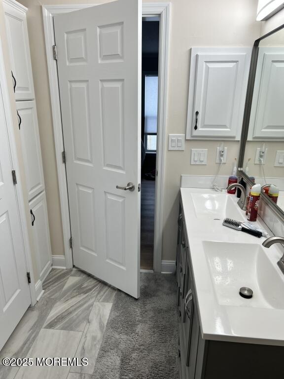 bathroom with double vanity, a sink, and baseboards