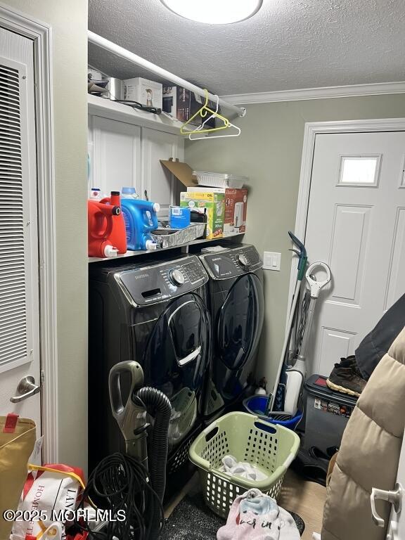 clothes washing area featuring ornamental molding, laundry area, independent washer and dryer, and a textured ceiling