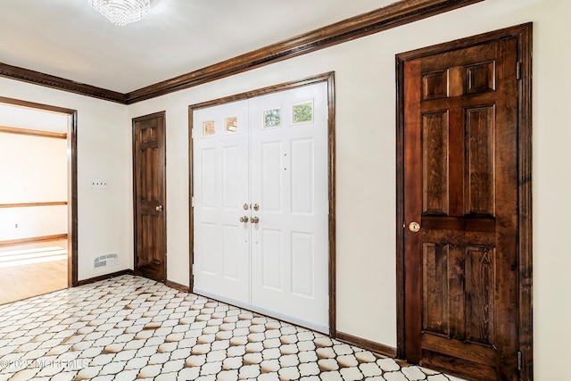 foyer featuring crown molding, light floors, and baseboards