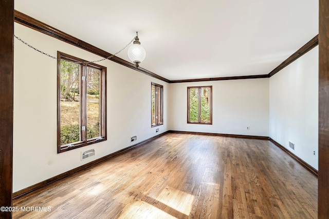 unfurnished room with visible vents, crown molding, baseboards, and wood finished floors