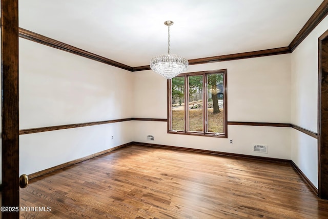 spare room featuring crown molding, baseboards, and wood finished floors