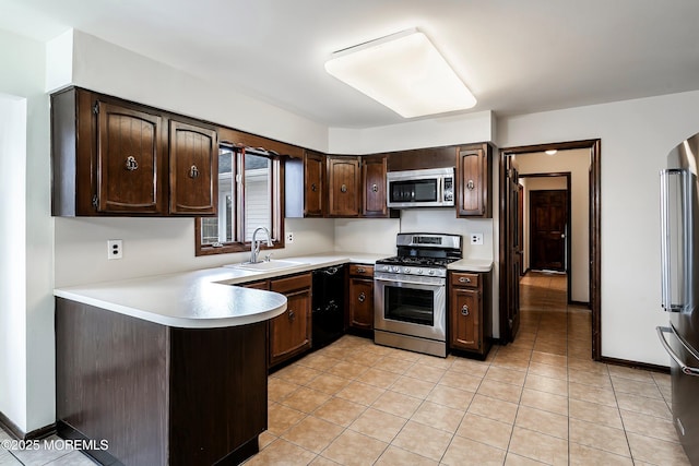 kitchen featuring appliances with stainless steel finishes, light countertops, a sink, and dark brown cabinets