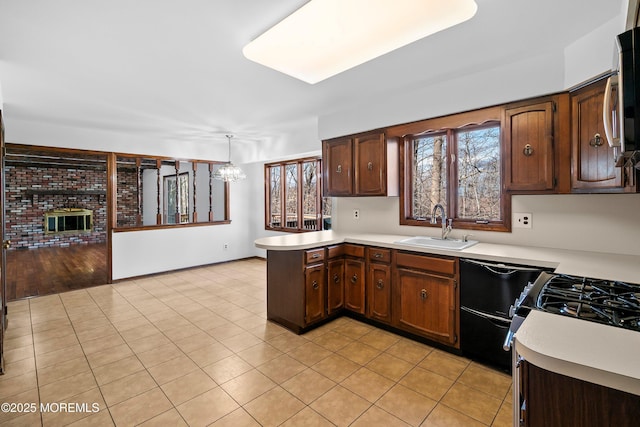 kitchen featuring light tile patterned floors, a peninsula, a sink, and light countertops