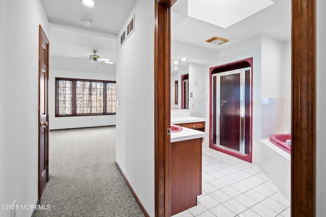 hall featuring a skylight, light colored carpet, recessed lighting, and light tile patterned flooring