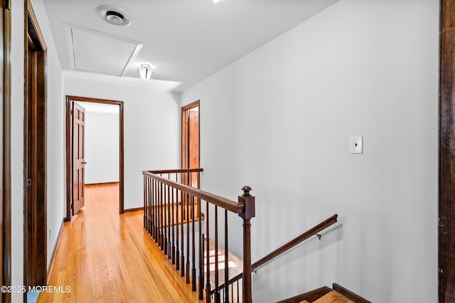 corridor with light wood-style floors, baseboards, and an upstairs landing