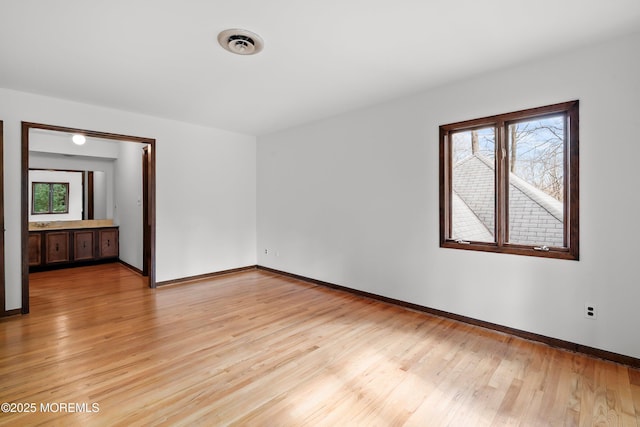 spare room with visible vents, light wood-style flooring, and baseboards