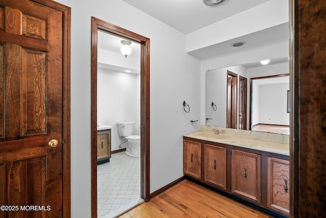 bathroom featuring toilet, wood finished floors, vanity, and baseboards