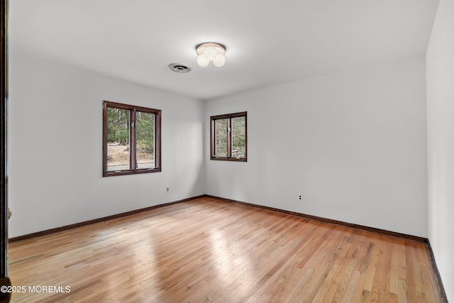 unfurnished room featuring light wood-type flooring, visible vents, and baseboards