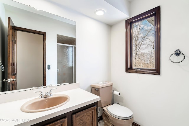 full bathroom featuring a stall shower, vanity, and toilet