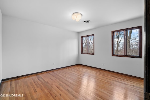 unfurnished room featuring baseboards, visible vents, and light wood finished floors