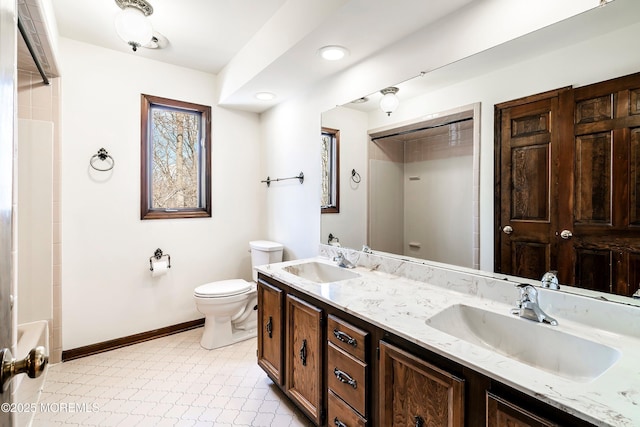 full bath with toilet, double vanity, a shower, and a sink