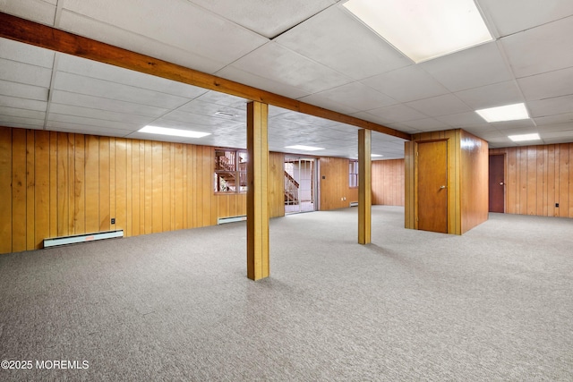 finished below grade area featuring carpet floors, wooden walls, and baseboard heating