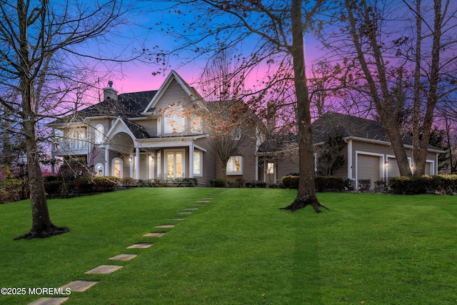 view of front of house featuring a garage, a chimney, and a yard