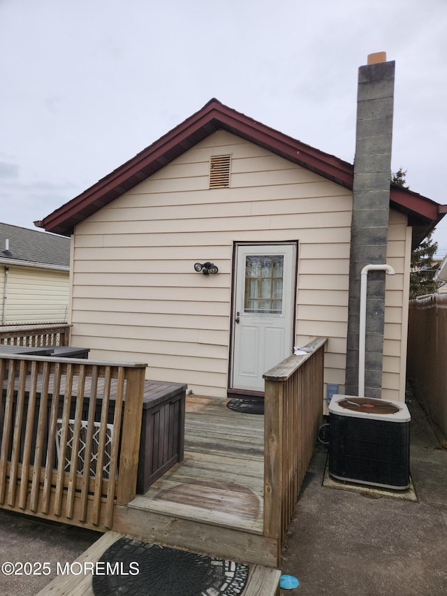 rear view of property with a chimney, cooling unit, and a wooden deck