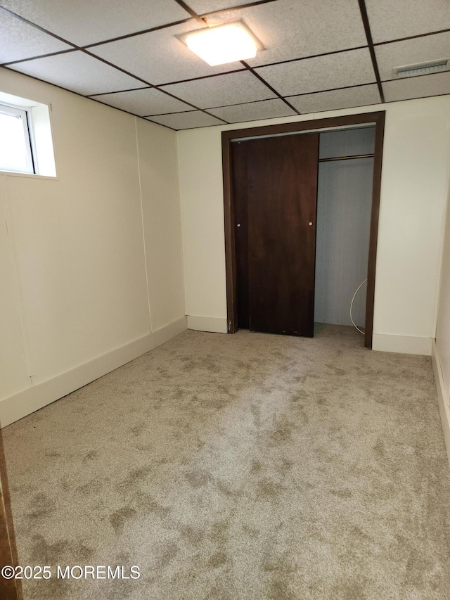 unfurnished bedroom with a paneled ceiling, visible vents, light carpet, and baseboards