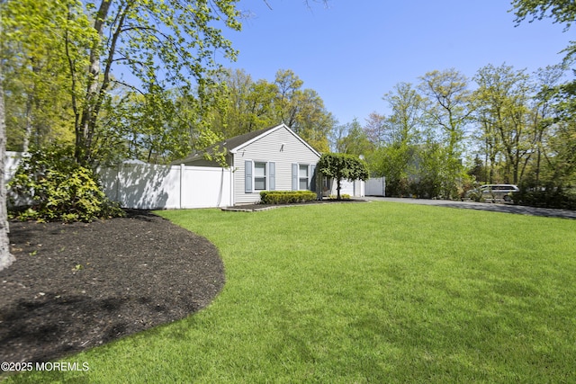 view of yard featuring an attached garage, fence, and aphalt driveway