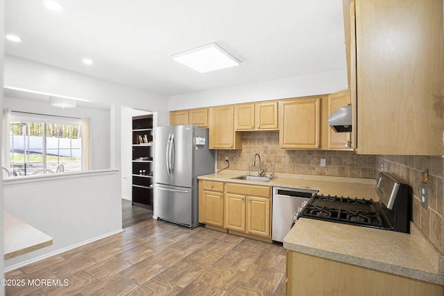 kitchen with a sink, light brown cabinets, light countertops, stainless steel appliances, and decorative backsplash