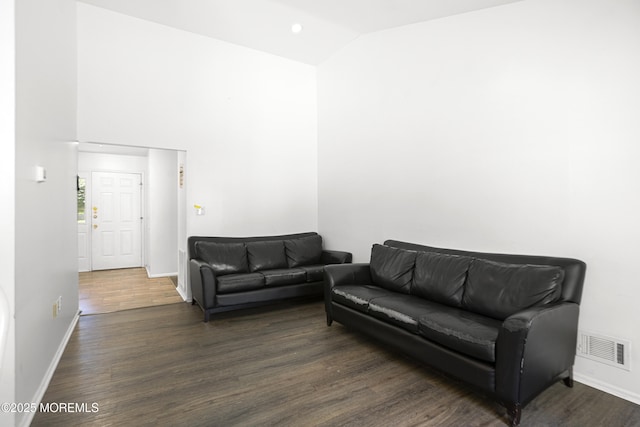 living area featuring baseboards, lofted ceiling, wood finished floors, and visible vents