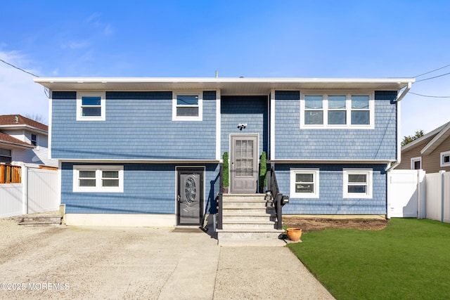 bi-level home featuring a front yard and fence