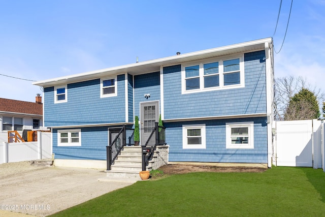 bi-level home featuring a front lawn, fence, and a patio area