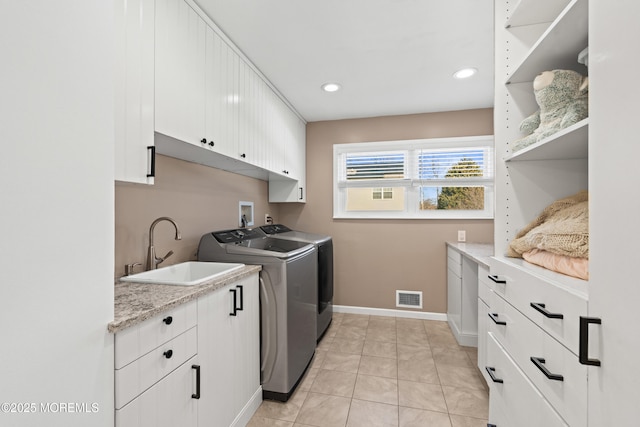 clothes washing area featuring baseboards, visible vents, cabinet space, a sink, and washer and dryer