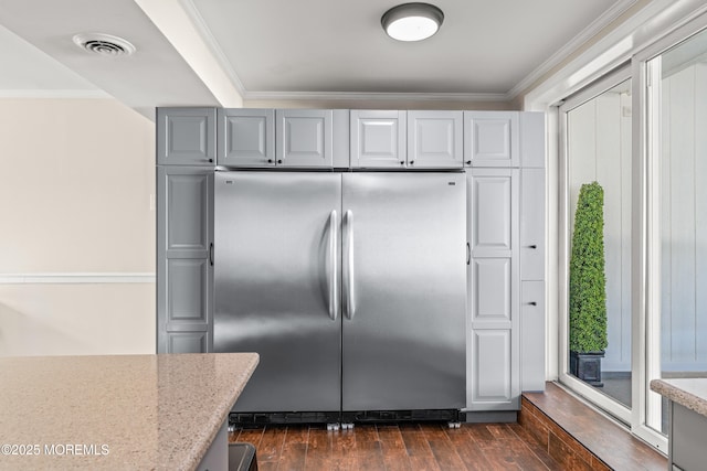 kitchen with visible vents, dark wood-style floors, stainless steel refrigerator, and crown molding