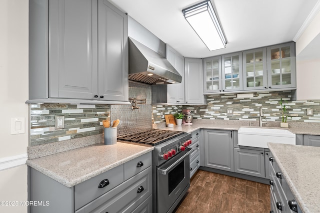 kitchen with dark wood finished floors, gray cabinets, a sink, high end stainless steel range, and wall chimney exhaust hood