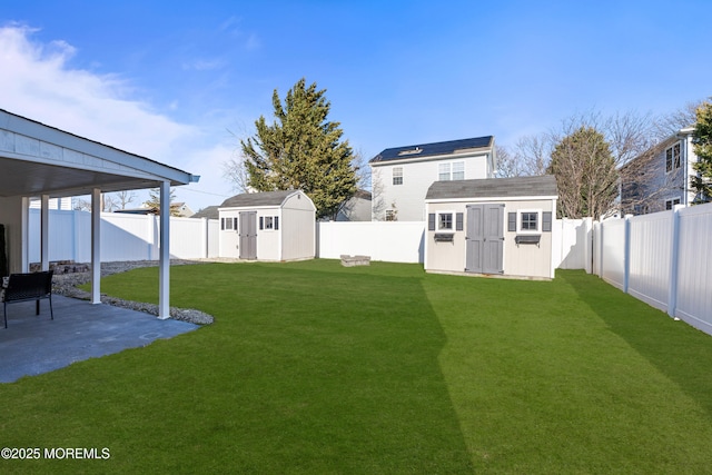 view of yard featuring a patio, a fenced backyard, an outbuilding, and a shed