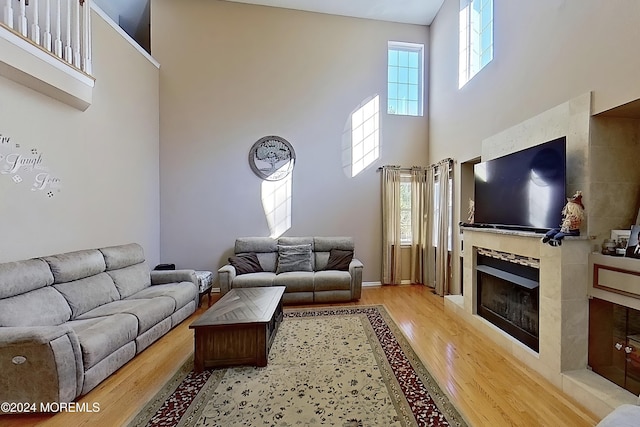 living room featuring light wood-style floors, a high ceiling, and a tiled fireplace