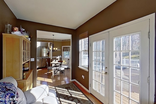 doorway with wood finished floors, french doors, baseboards, and an inviting chandelier