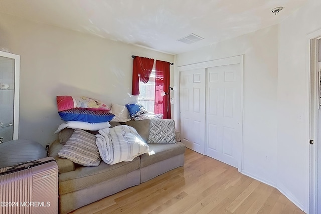 bedroom featuring light wood finished floors, visible vents, and a closet