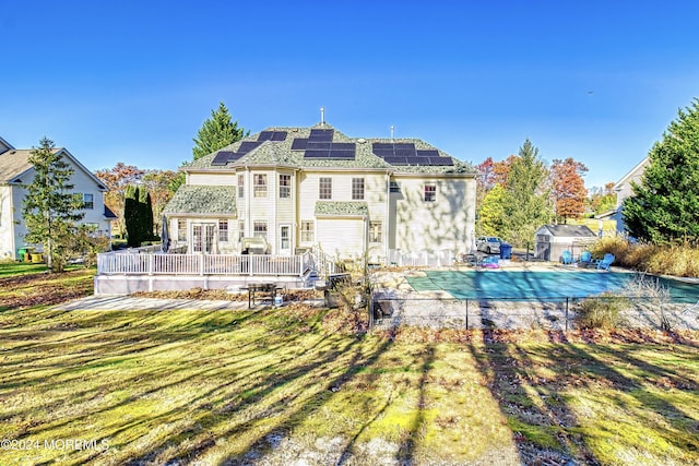 rear view of house featuring a fenced in pool, a yard, solar panels, a deck, and an outdoor structure