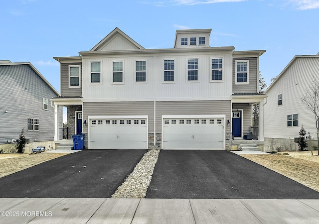 view of front of property featuring driveway, stone siding, and an attached garage