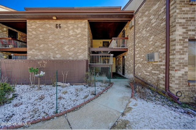 exterior space with a balcony, fence, and brick siding