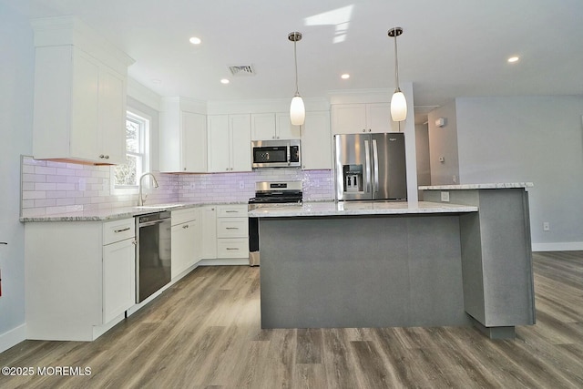 kitchen featuring visible vents, white cabinets, appliances with stainless steel finishes, a center island, and pendant lighting