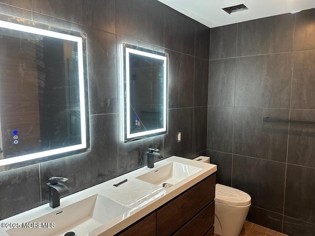 bathroom with tile walls, double vanity, backsplash, toilet, and a sink