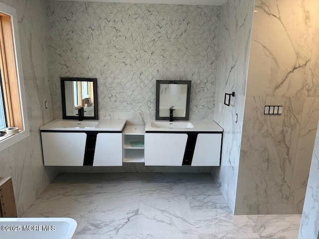 full bath with two vanities, a sink, and stone wall