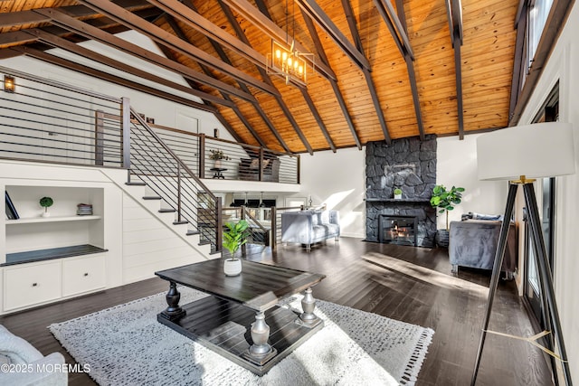 living area featuring a stone fireplace, dark wood-type flooring, wood ceiling, and stairway
