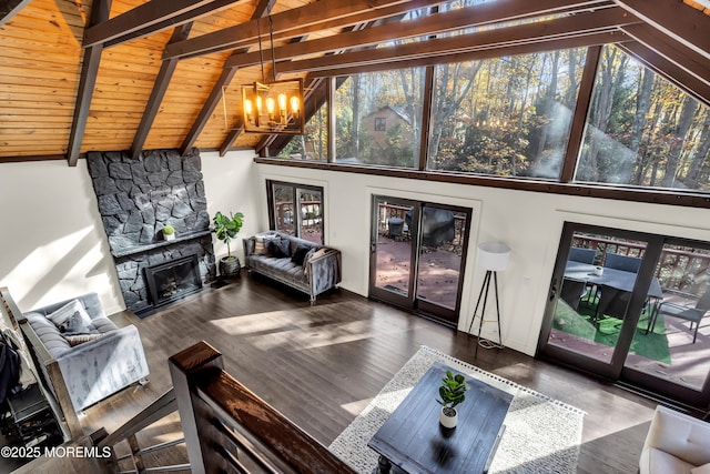 living area featuring plenty of natural light, beamed ceiling, a fireplace, and a notable chandelier