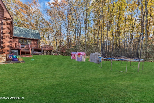 view of yard with a trampoline, a deck, and stairs